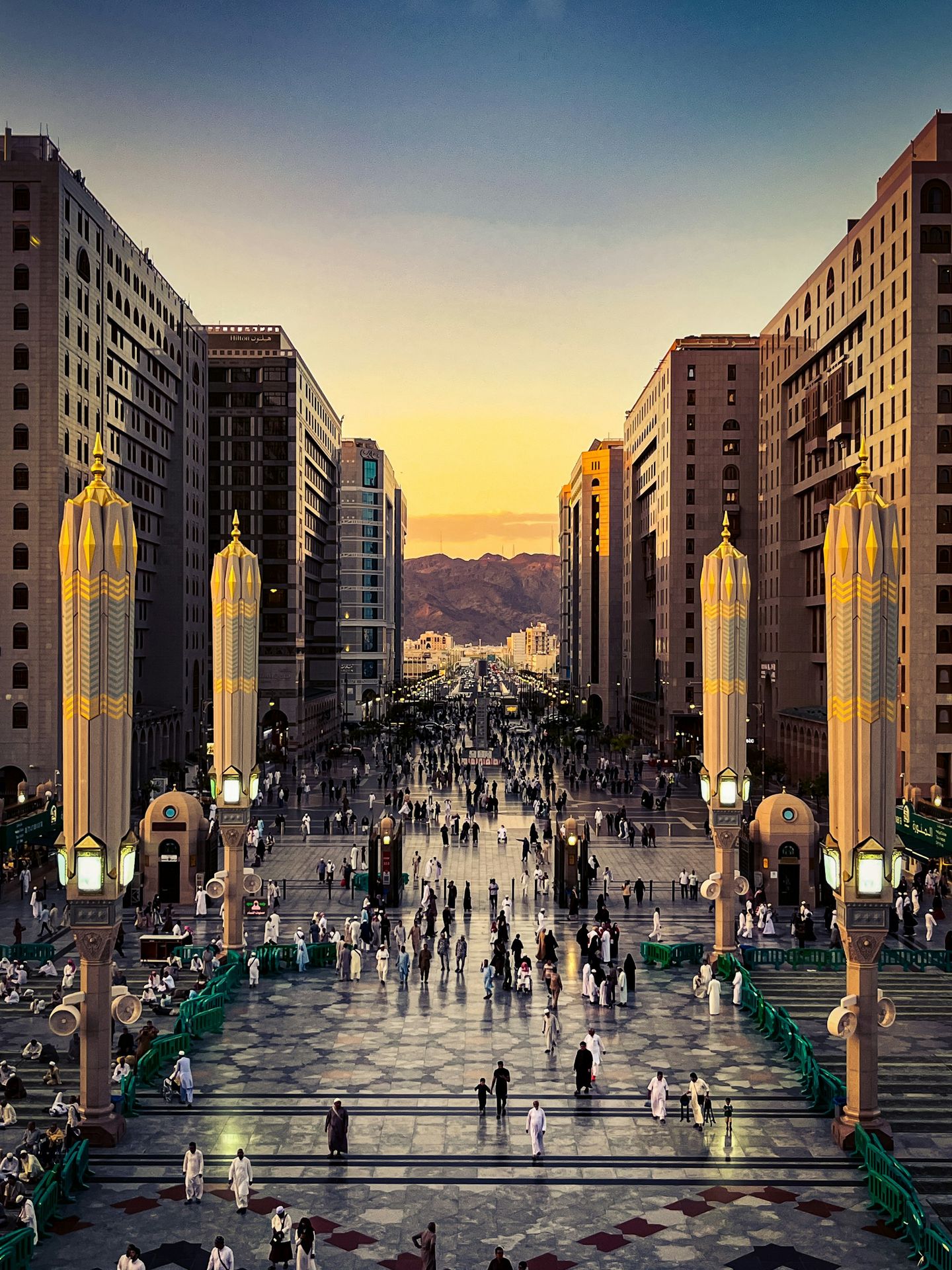A group of people walking down a street next to tall buildings